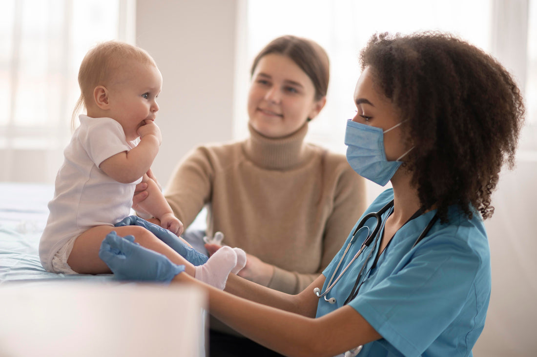 Baby being examined by a healthcare professional wearing gloves and a mask, while the mother smiles in the background