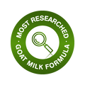 A circular green badge with white text reading 'MOST RESEARCHED GOAT MILK FORMULA' and a magnifying glass icon in the center